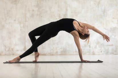 Das Bild zeigt eine Frau, die Pilates und Yoga praktiziert und an den angebotenen Kursen teilnimmt.