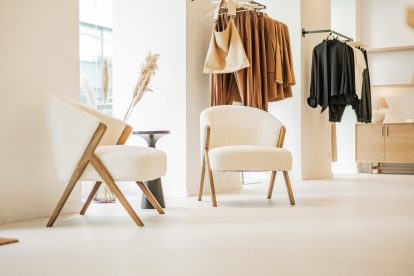 Foto, das das elegante Interieur des Ukiyo Wien Ladens zeigt, mit Kleidungsstücken, die zum Kauf angeboten werden, und zwei stilvollen Stühlen, auf denen Kunden sich entspannen können.