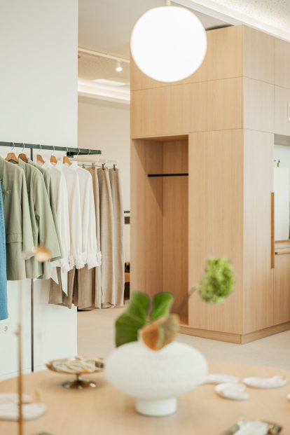 Photo showcasing the elegant and minimalist interior of the Ukiyo Vienna store, featuring wooden accents and displays of clothing items available for purchase.