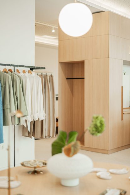 Photo showcasing the elegant and minimalist interior of the Ukiyo Vienna store, featuring wooden accents and displays of clothing items available for purchase.