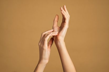 Close up of beautiful woman hands isolated against cream yellow background. Elegant and graceful female hands with slender fingers. Beauty woman with light manicure on nails.